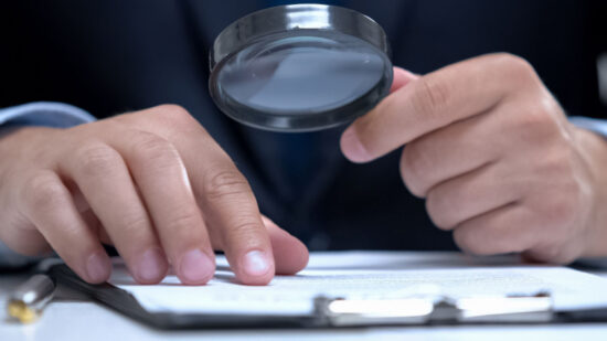 Attorney reading document with magnifier, studying case in detail, investigation-Shutterstock_1539656501